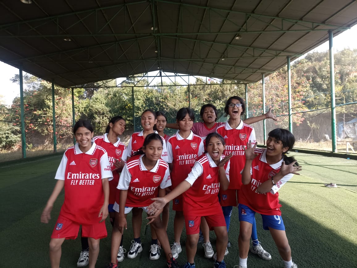 A girls' soccer team poses for a photo in their uniforms.