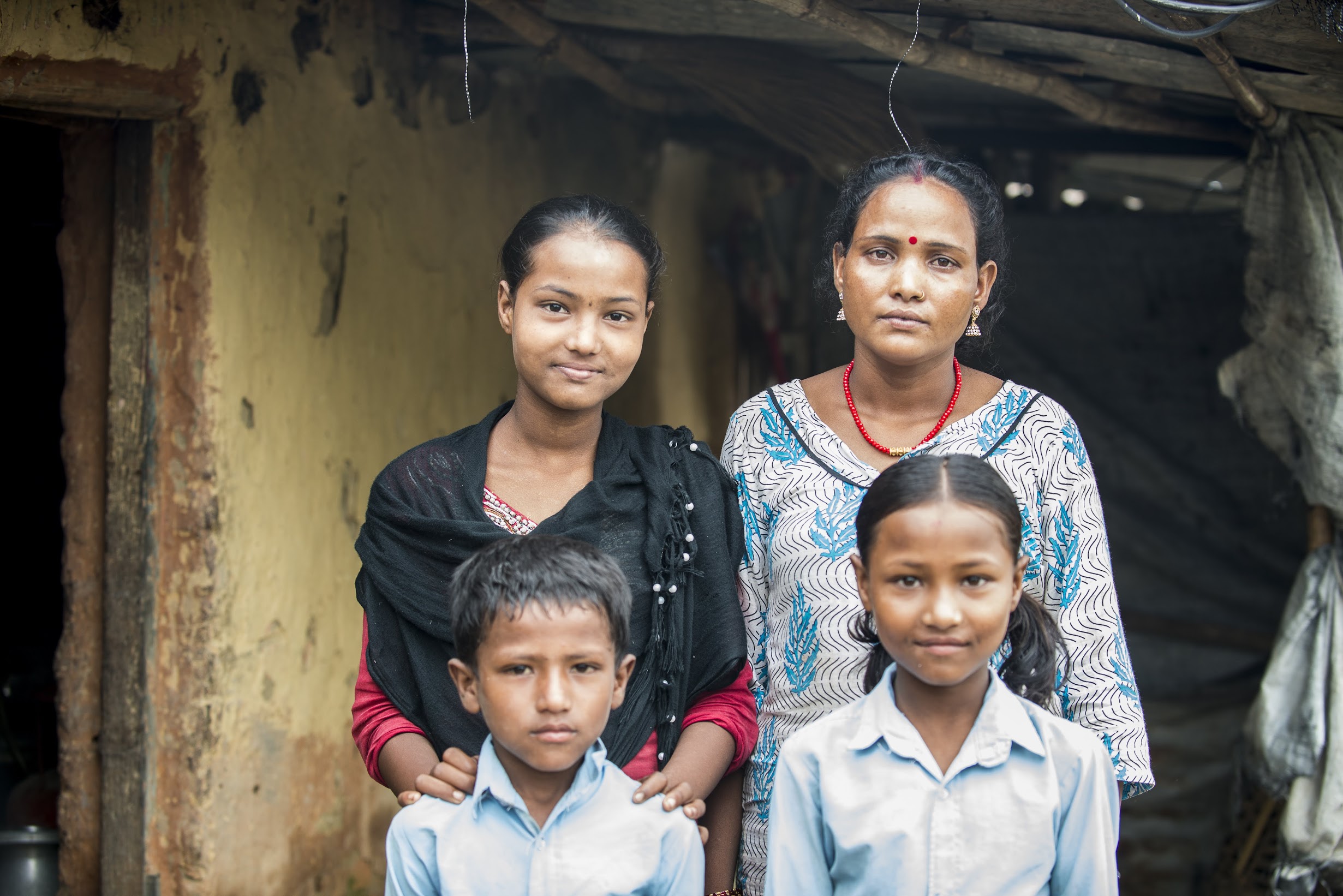 Dhana poses with her three children of her four children before they head to school and she heads to the Women’s Center