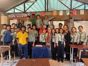 A group of students and teachers fills a classroom and smiles for the camera.