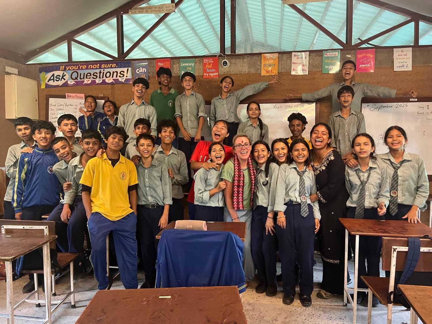 A group of students and teachers fills a classroom and smiles for the camera.