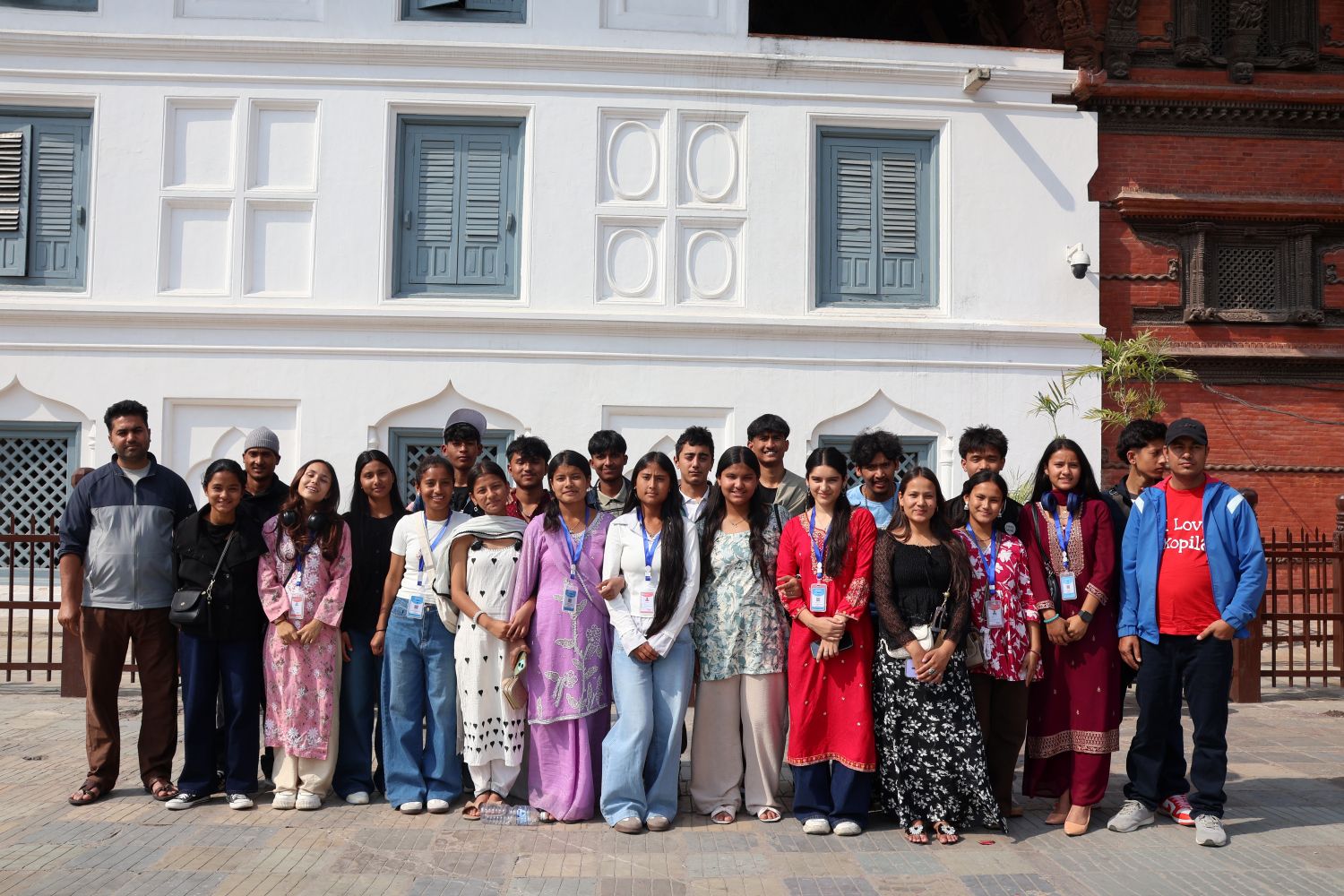 A group of high school student stands in front of a starkly white building.