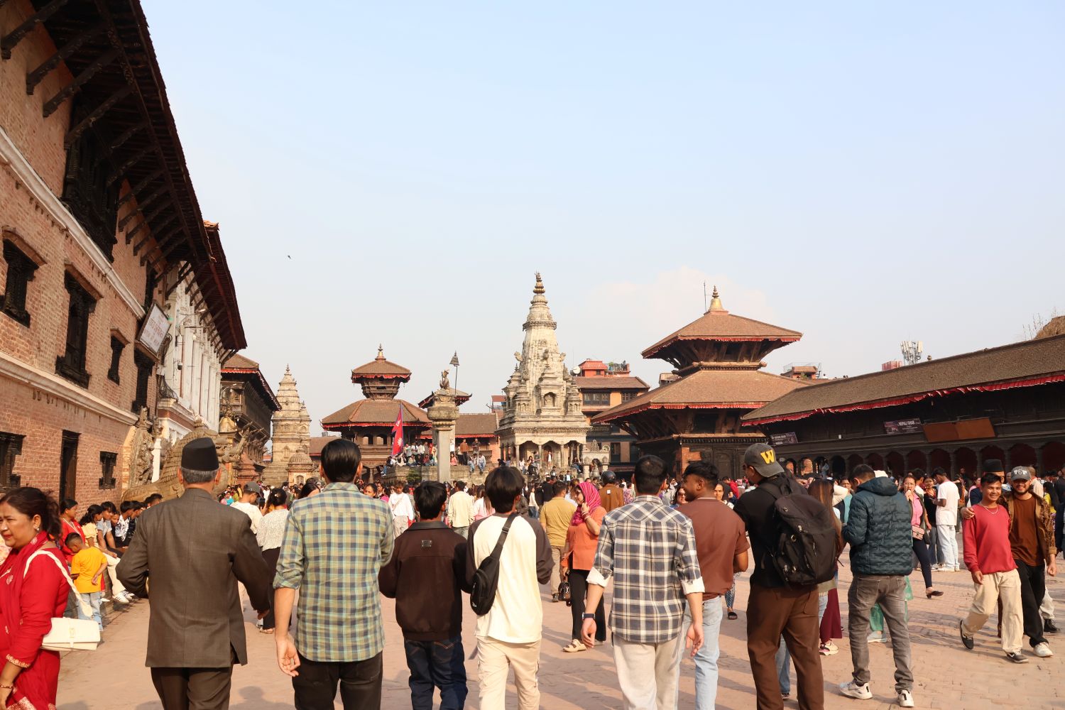 Students walk down a street toward a brown stone temple.