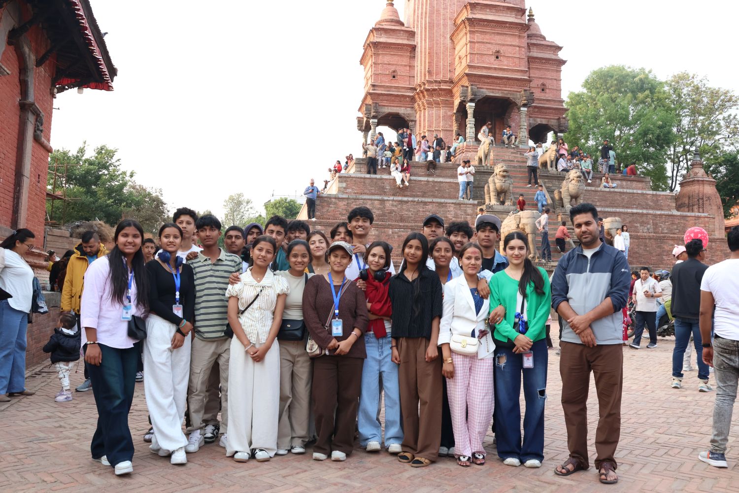 A group of students poses in front of a brown stone temple.
