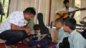 A teacher helps students with musical instruments.