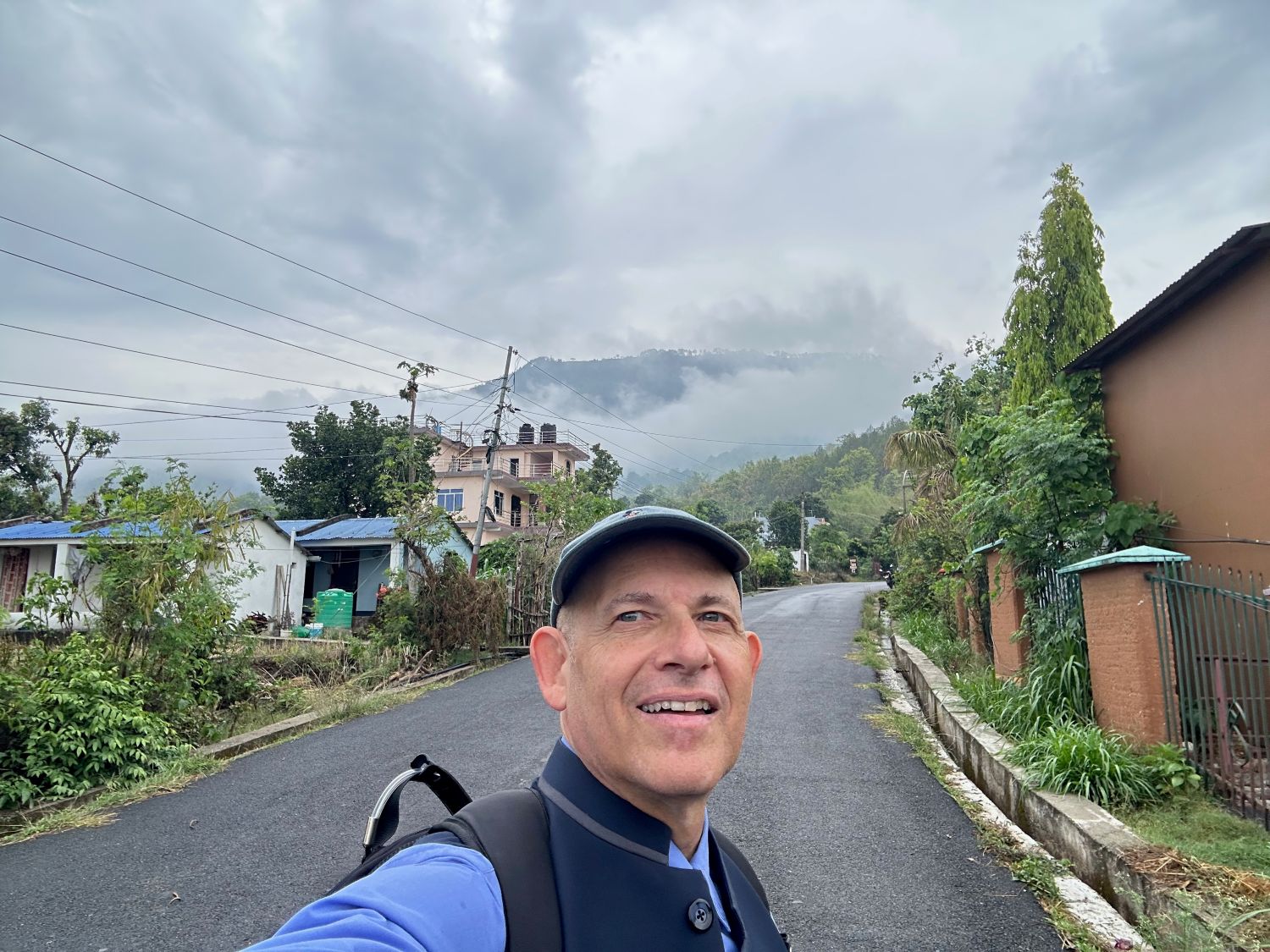 A man stands on an empty road in front of a misty mountain scene.